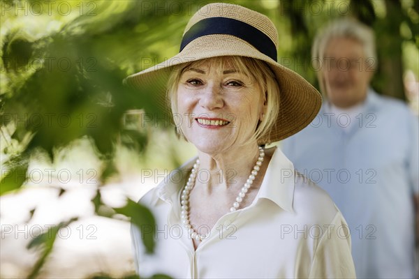 Summery dressed older woman together with her grey-haired man in the park