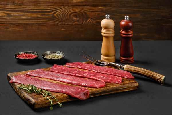 Raw beef strips on wooden cutting board