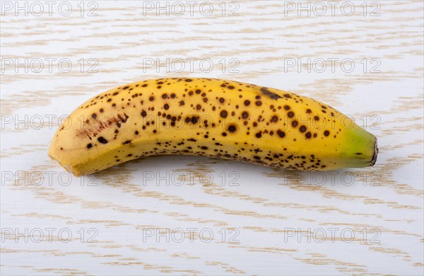 Single yellow freckled bananas on a wooden texture
