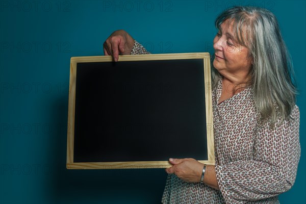 Older white-haired woman holding a blackboard with space for copying text