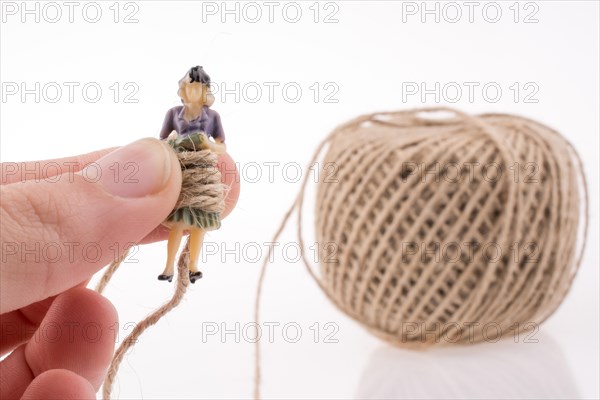 Woman figure in hand beside a linen spool of thread on a white background