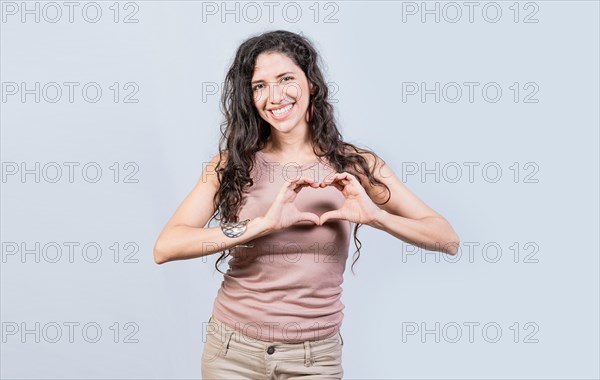 Smiling young woman making heart shape with her hands. Teen girl making heart shape with her hands