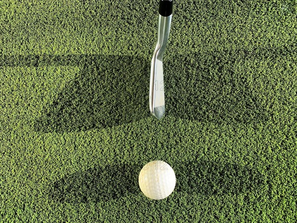 Golf Club and Ball with Double Shadow on Mat on Driving Range in Switzerland
