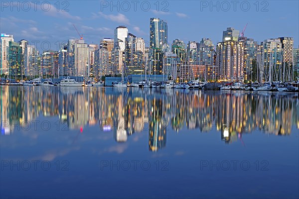 Illuminated skyscrapers and pleasure boats reflected in the calm water