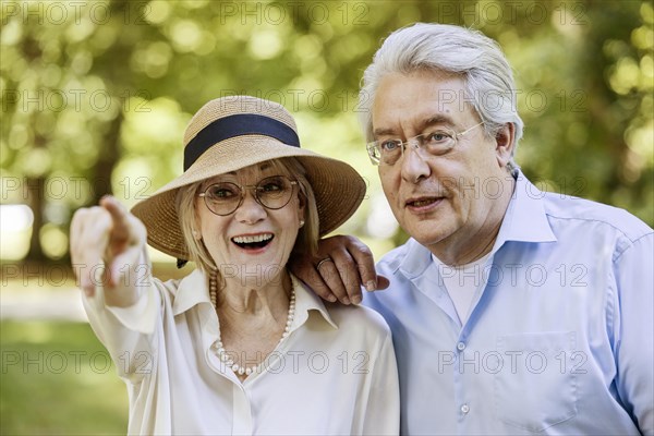 Summery dressed older woman together with her grey-haired man in the park