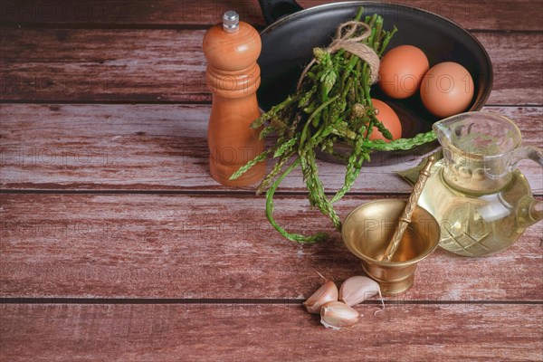 Bunch of wild asparagus in a frying pan with eggs