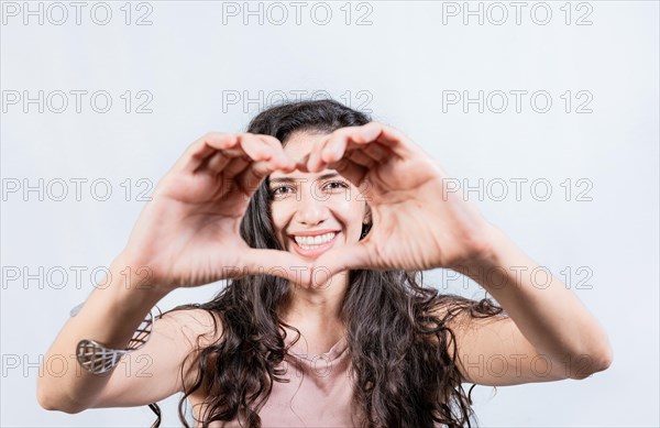 Happy girl making heart shape with hands isolated. Smiling young woman making heart shape with her hands. Teen girl making heart shape with her hands