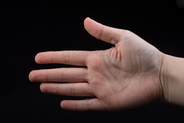 Five fingers of a child hand partly seen in black background