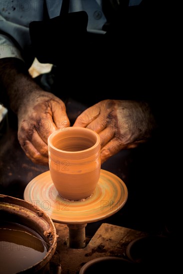 Potter`s hands shaping up the clay of the pot