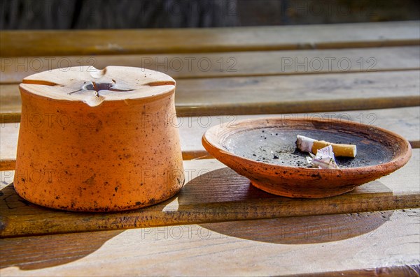 Stylish ashtray with cigarette butt on a wooden table