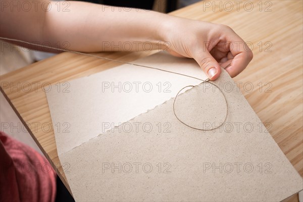 Close-up detail of woman's hands sewing a handmade notebook made in her workshop