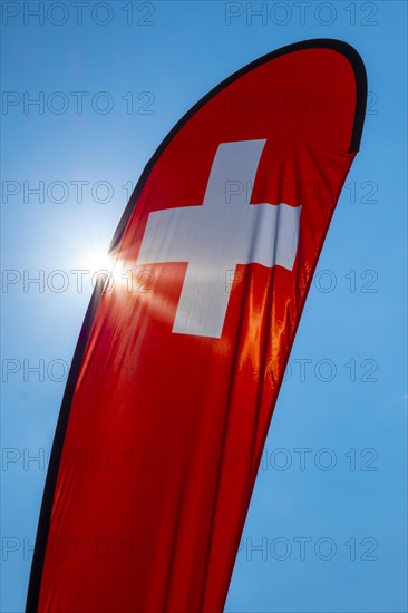 Swiss Banner Flag with Sunlight and Against Blue Sky in Switzerland