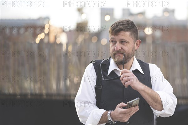 Portrait of businessman walking in the street texting with his phone