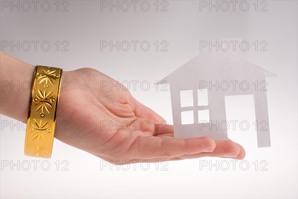 Hand holding a paper house with a golden bracelet