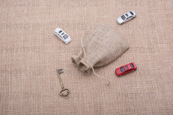 Key and toy cars around a sack on a linen canvas