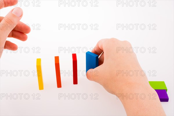 Hand playing with colored domino on white background