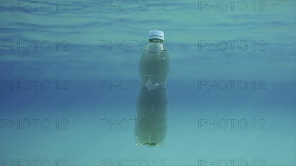 Green plastic bottle drifting under surface of blue water. Plastic pollution of Ocean