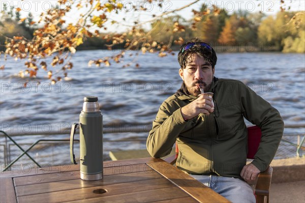 Latin man enjoying the sunset at the river while drinking mate