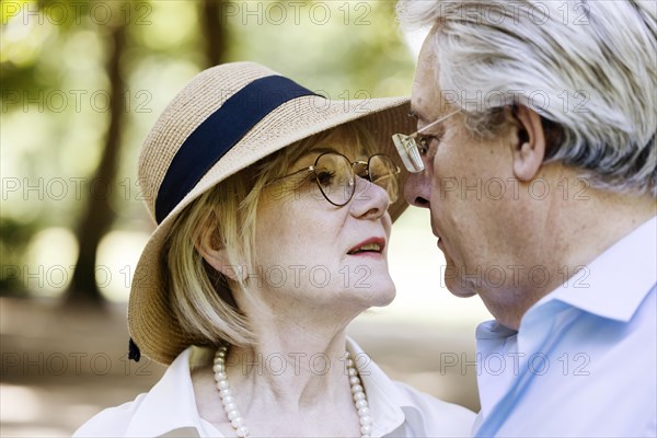 Summery dressed older woman together with her grey-haired man in the park