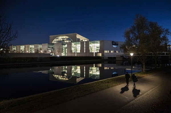 Two people stand out in front of the Federal Chancellery at blue hour