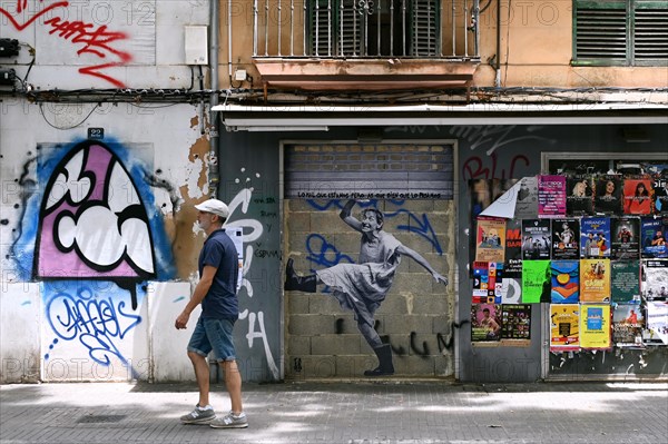 Passers-by in front of a house wall with a stencil