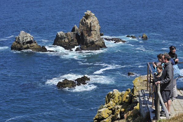 Tourists and birdwatchers looking at sea birds along the rocky coast at Cap de Sizun