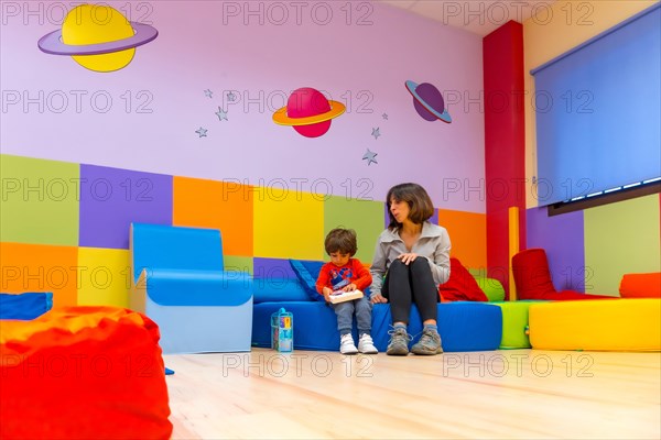 Woman teacher playing with a child sitting reading a book