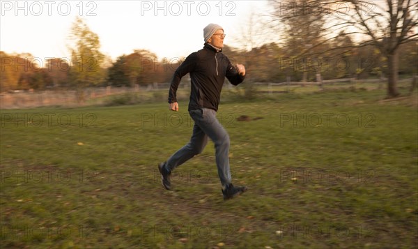 Man doing early morning exercise in autumn in a meadow.