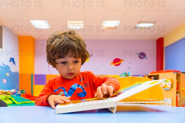 Portrait of a boy sitting at a table reading a story book