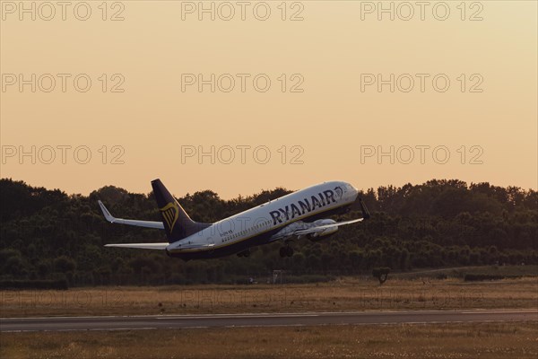 Passenger aircraft Boeing 737-8AS of the airline Ryanair taking off in the evening glow at Hamburg Airport