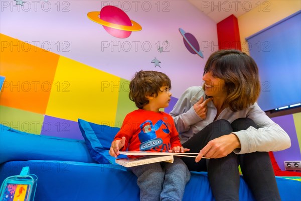 Woman teacher playing with a child reading a book and having fun