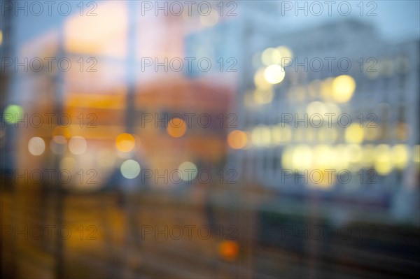 Daydream photographed from the window of a train. Blurred image with lights of a city and the reflection of a train compartment