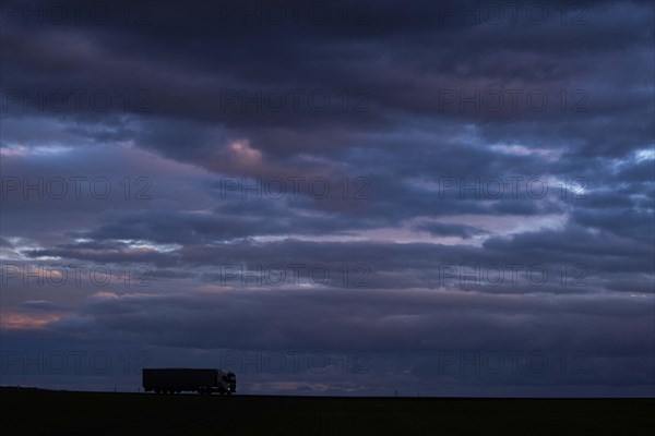 A lorry stands out on a country road at blue hour in Vierkirchen