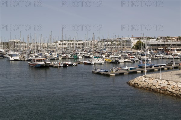 Tour boat with tourists and sailing boats in the marina of Lagos