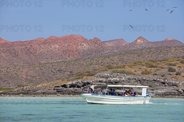 Tourist boat sailing along the rocky coastline of Isla Espiritu Santo