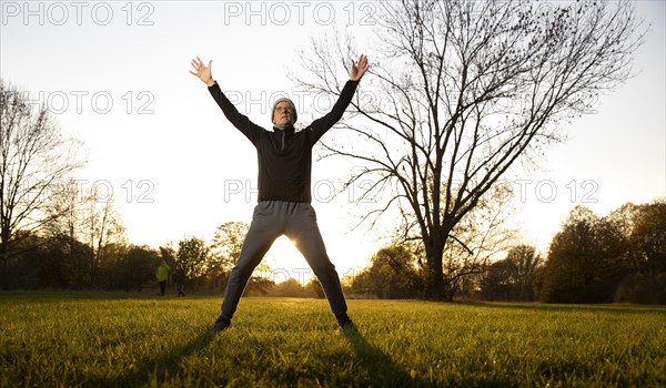 Man doing early morning exercise in autumn in a meadow.