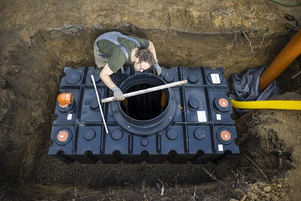 A man installs a water cistern in the garden next to his house to be able to water his garden with rainwater. Berlin