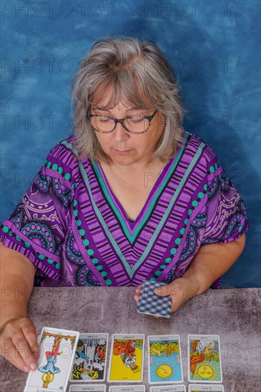 Older woman with white hair and glasses casting tarot cards