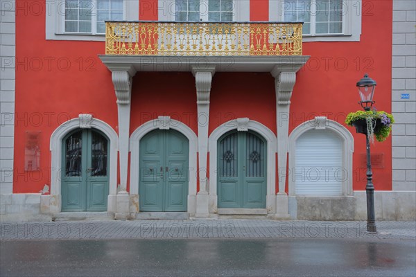 House wall of town hall with balcony and golden railing and doors