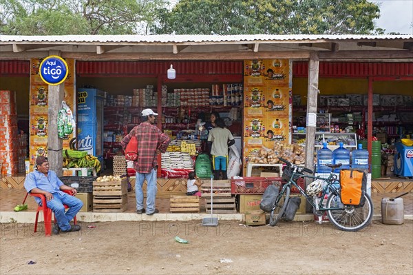 Touring cyclist buying food at roadside grocery shop