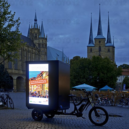 Illuminated advertising on cargo bike on the cathedral square in the evening