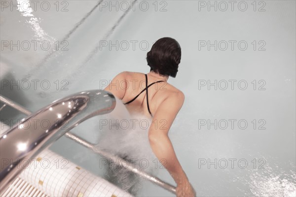 Woman Relaxing in a Hydro Massage Pool with Falling Water on Her Spine in Switzerland