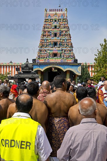 Hindus and a steward on the main festival day at the temple festival in front of the Hindu temple Sri Kamadchi Ampal