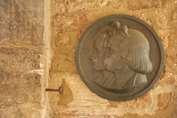 Monument and medallion of the Brothers Grimm on the stone wall of the castle