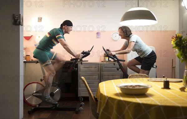 Man and woman on spinning wheels in their kitchen during the Corona Crisis lockdown