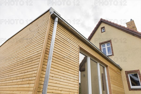 Symbolic photo on the subject of building with wood. The extension of a house is clad in larch wood. Berlin