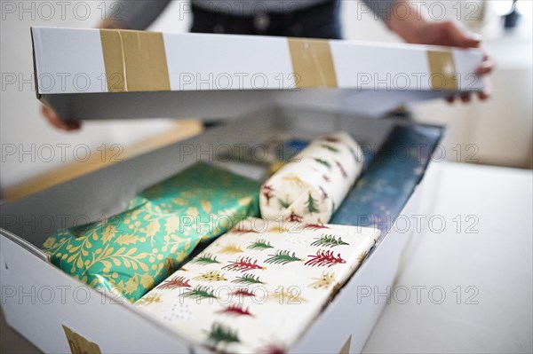 Symbolic photo on the subject of sending Christmas presents by post. A woman opens a parcel with Christmas presents. Berlin