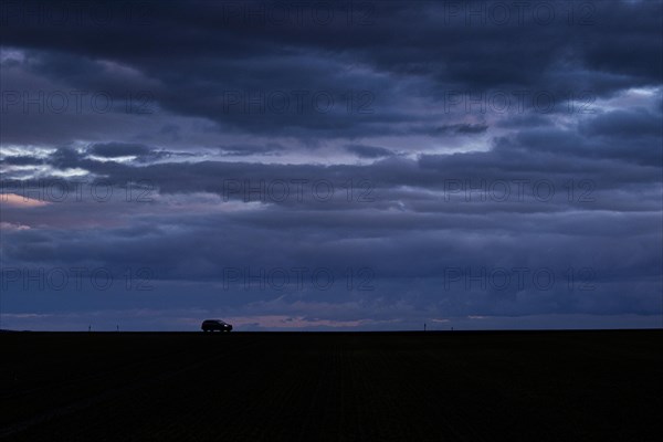 A car stands out on a country road at blue hour in Vierkirchen