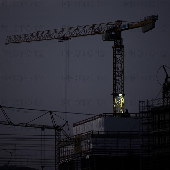 A worker draws on scaffolding and in front of a crane on a newly built house