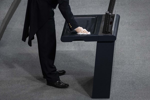 An usher disinfects the lectern during the special event in the German Bundestag to mark the 75th anniversary of the United Nations. Berlin